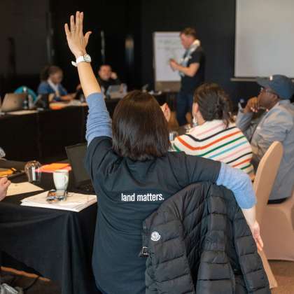 Woman raising her hand with "Land Matters" on t-shirt